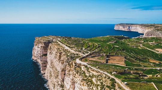 green grass on rocky mountain near body of water during daytime in Munxar Malta