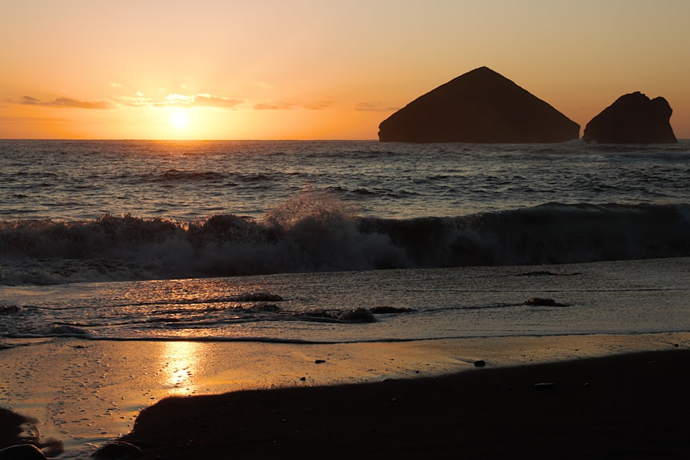 ocean waves crashing on shore during sunset