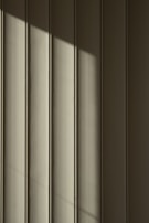 Vertical panels with a smooth texture are highlighted by a diagonal shadow that creates a play of light and dark across the surface.