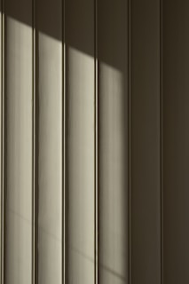 Vertical panels with a smooth texture are highlighted by a diagonal shadow that creates a play of light and dark across the surface.