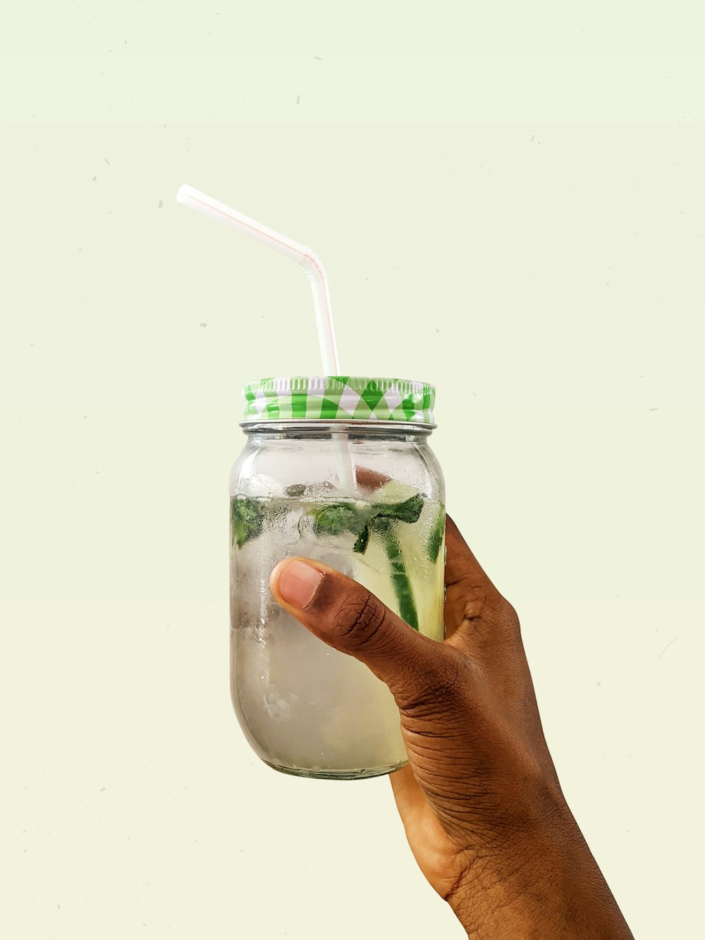 person holding clear glass jar with green and white lid