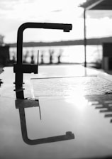 Close-up of a sleek, shiny PTMT swan neck tap installed in a contemporary bathroom setting.