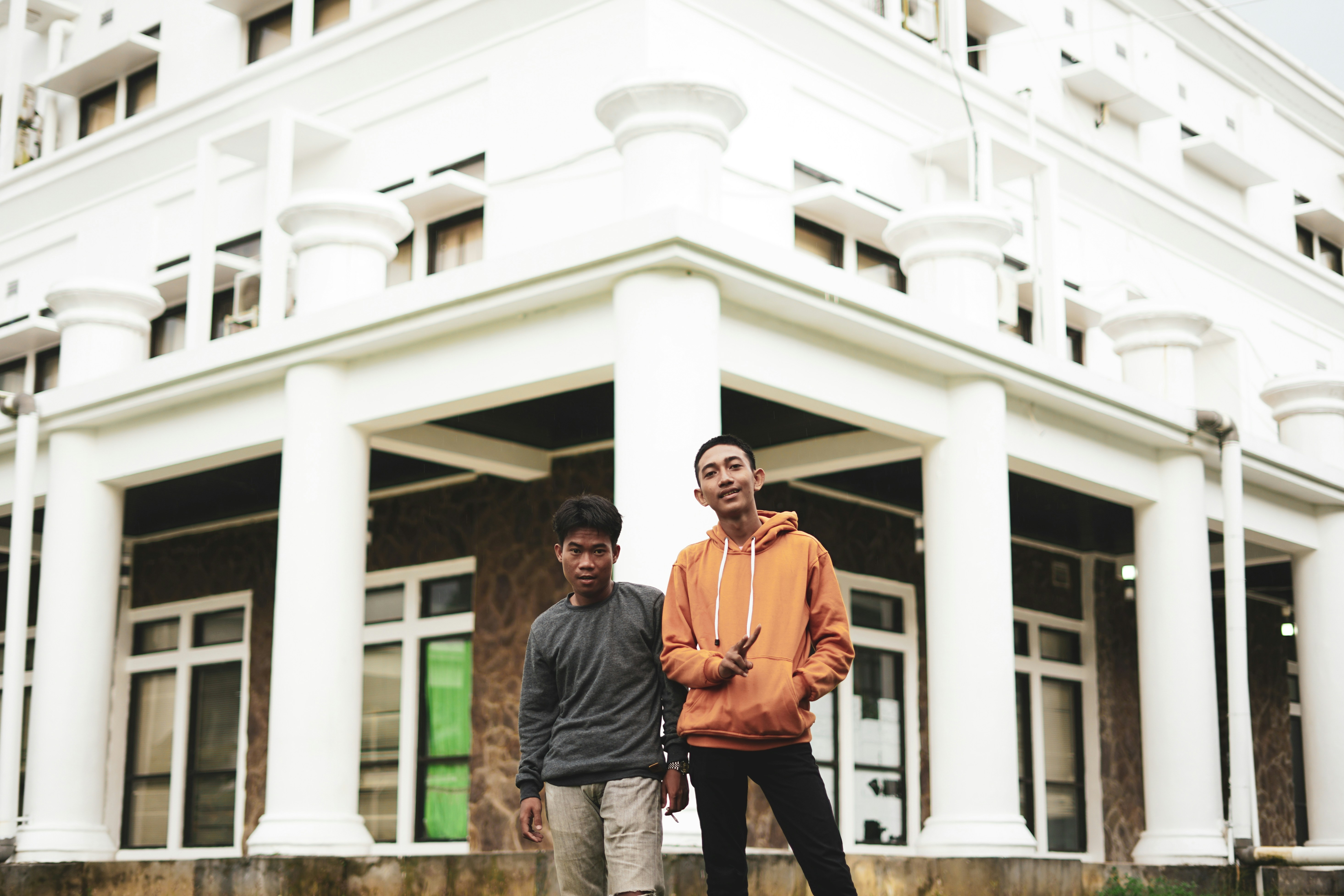 Mann in orangefarbener Jacke steht neben Mann im schwarzen Langarmhemd