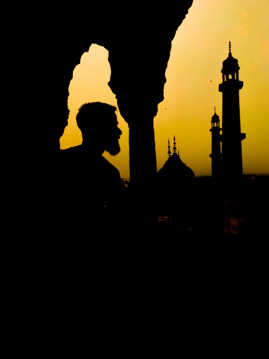 silhouette of man and woman standing near tower during daytime in Lucknow India