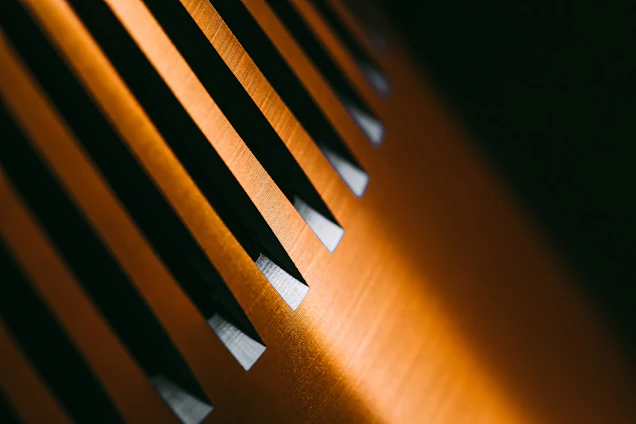 Close-up of a matte black surface with fine golden lines creating an abstract architectural pattern.