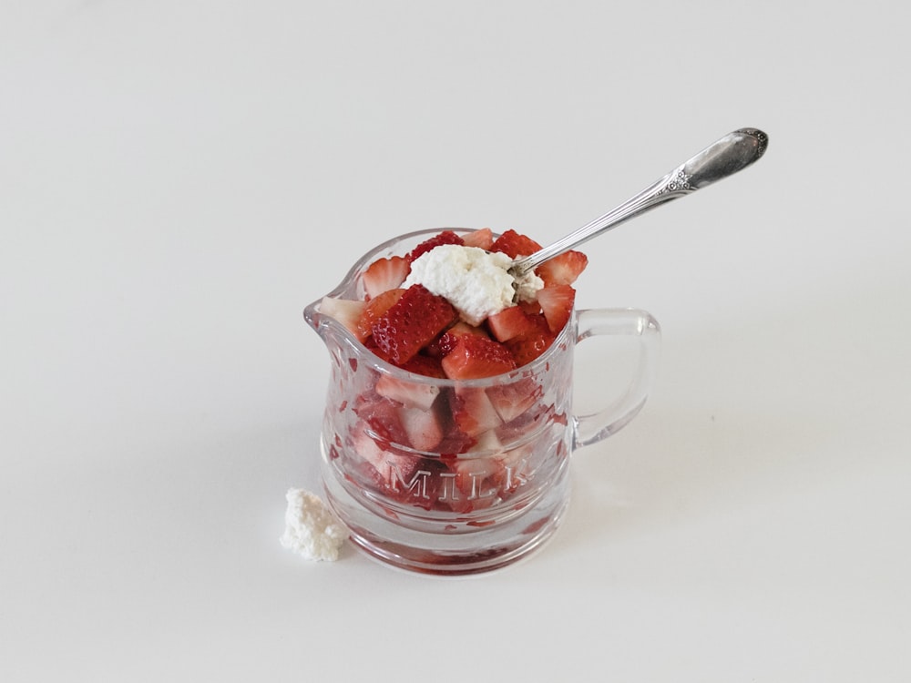 ステンレス製のスプーン付き透明なガラスマグカップに入ったイチゴのアイスクリーム