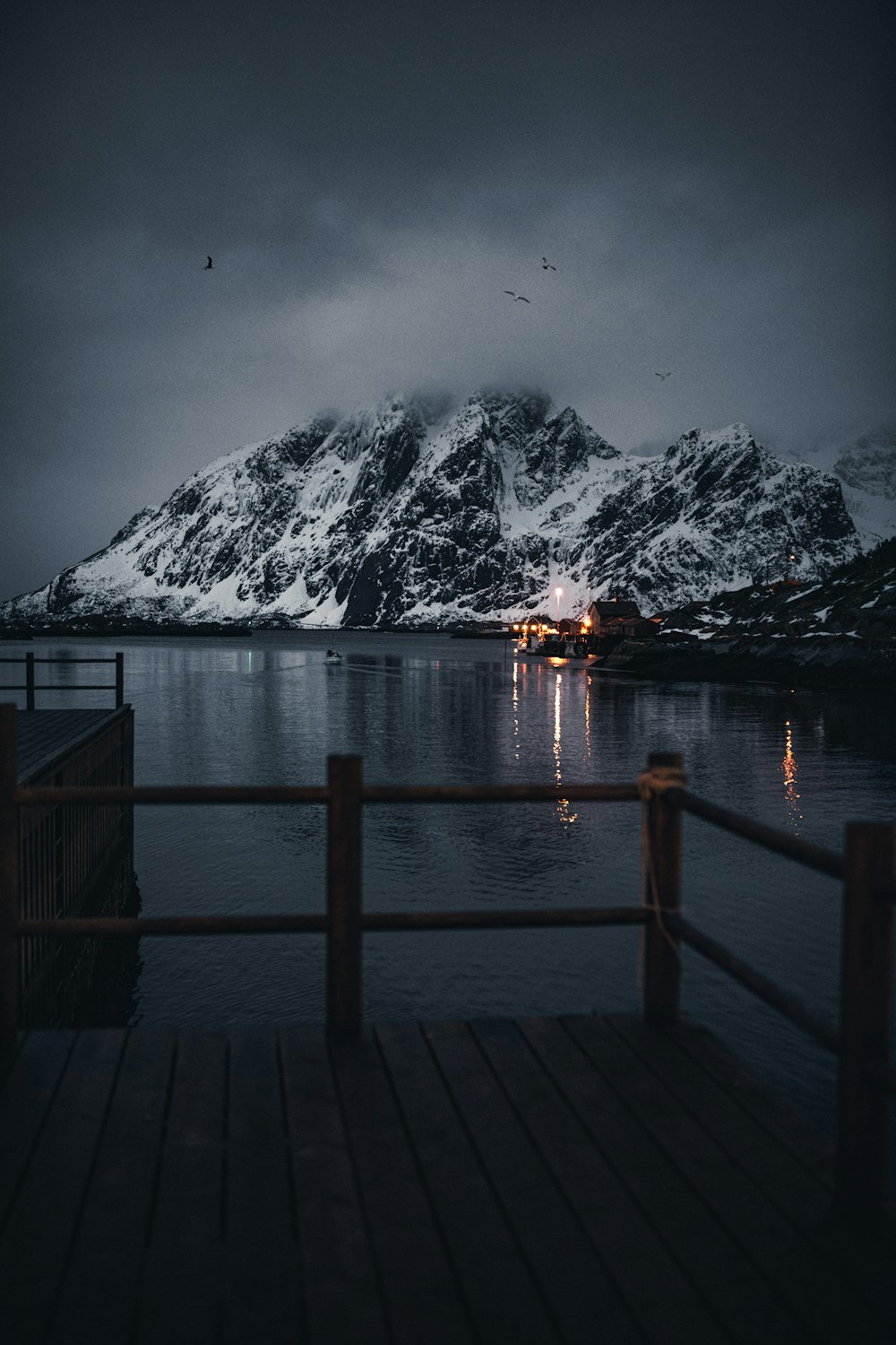 brown wooden dock on lake near snow covered mountain