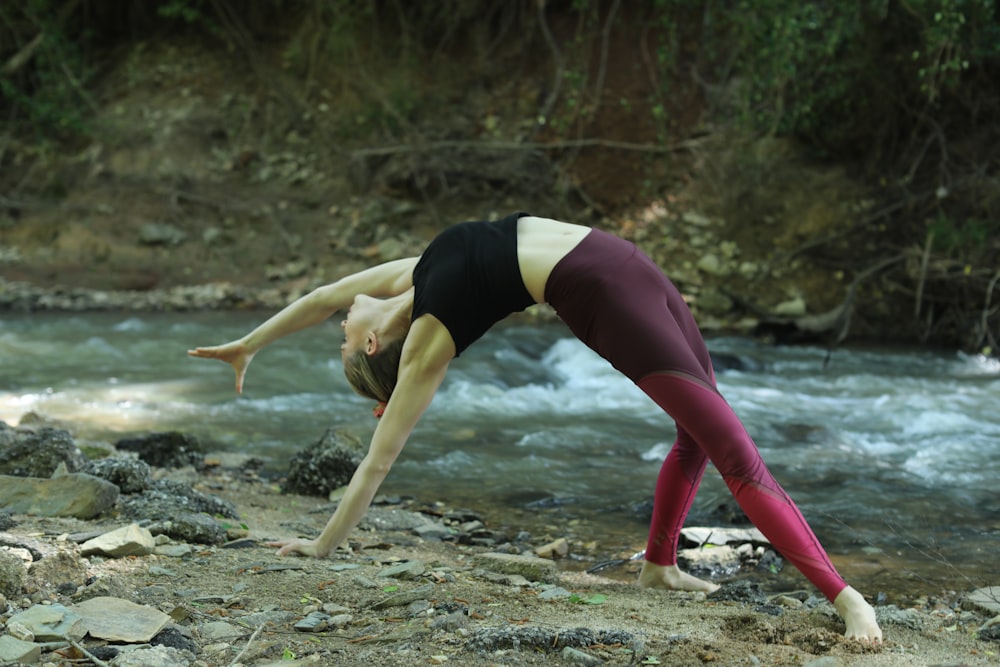 woman in black tank top and pink leggings doing yoga on brown sand during daytime