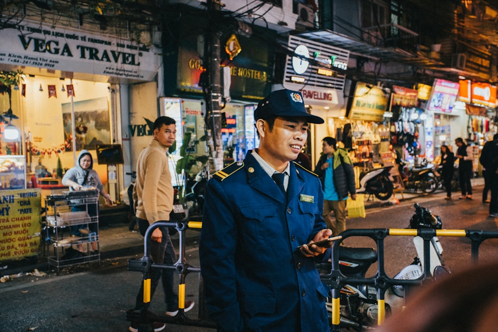 man in blue uniform standing near people during daytime