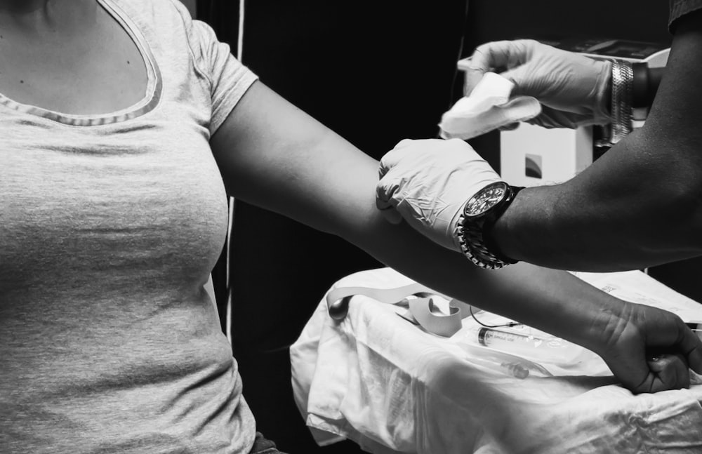 Graustufenfoto eines Mannes in T-Shirt und Uhr mit Smartphone