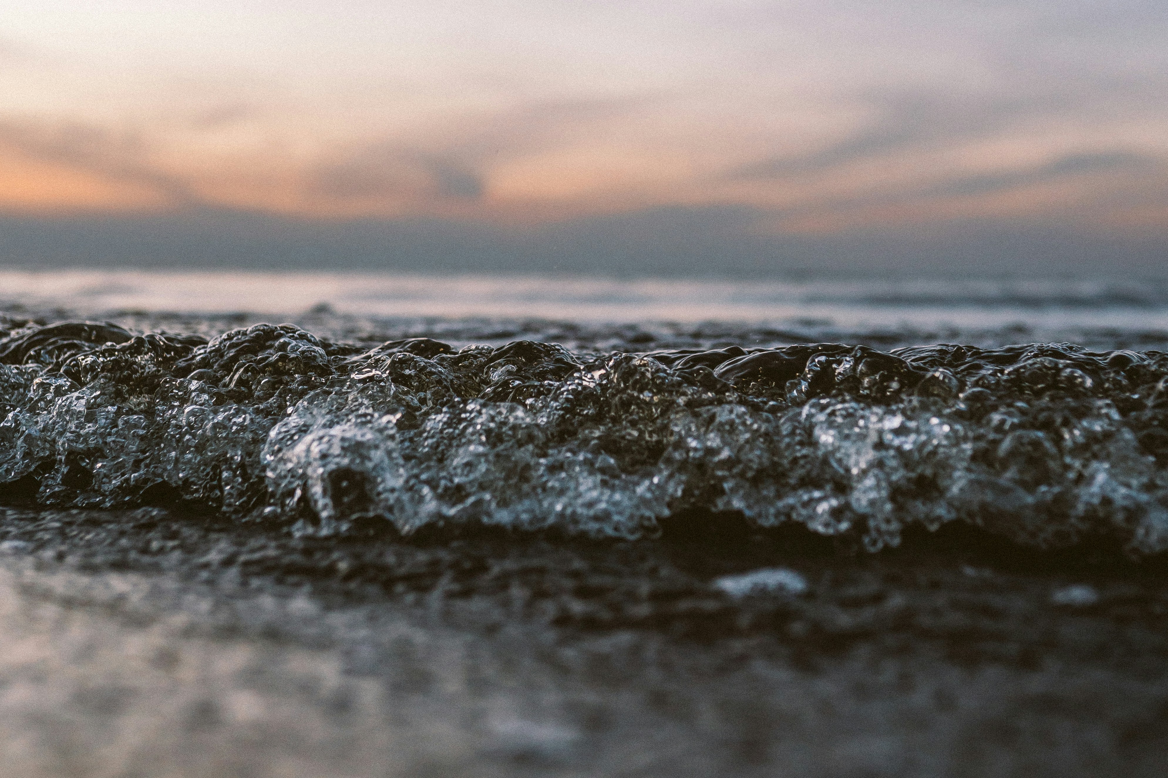 ocean waves crashing on shore during sunset