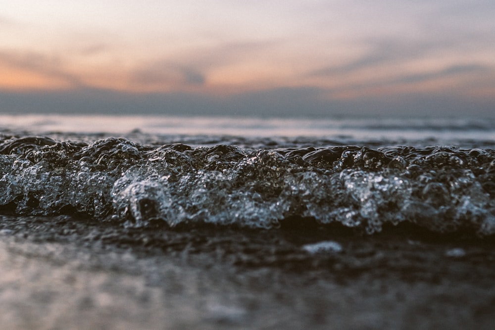 ocean waves crashing on shore during sunset