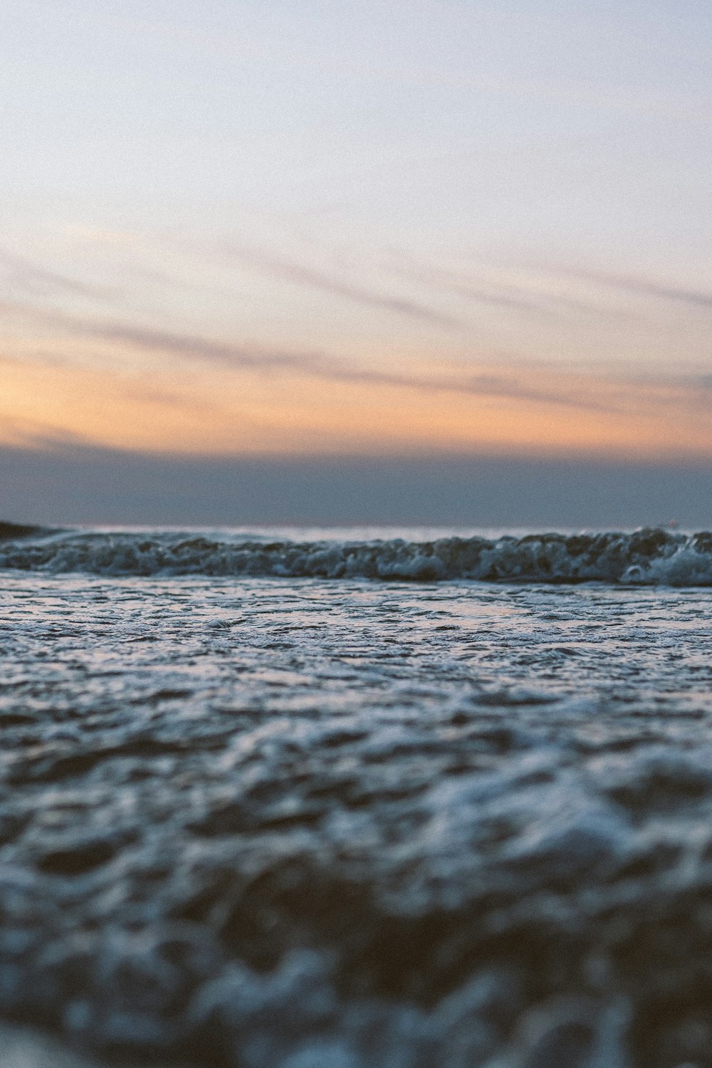 ocean waves crashing on shore during sunset