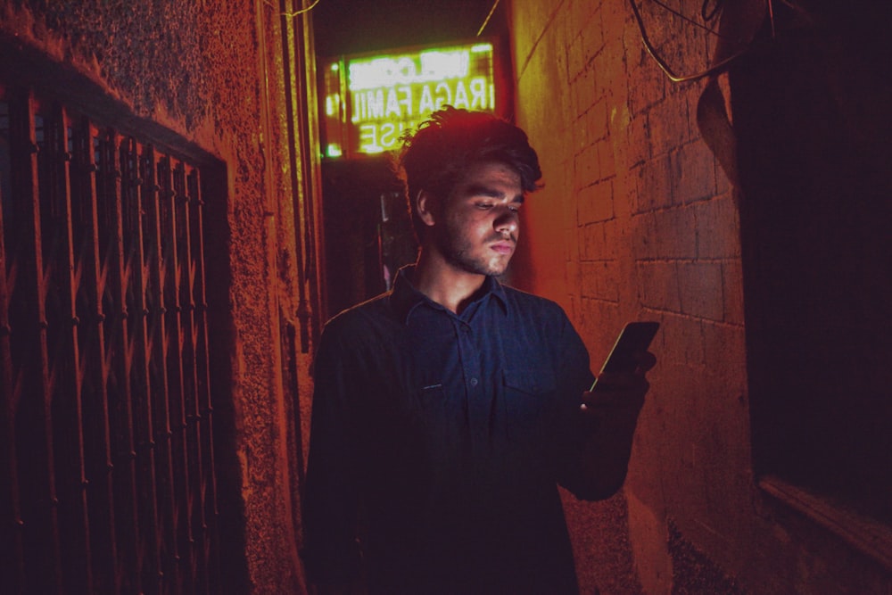 man in black dress shirt standing near red brick wall