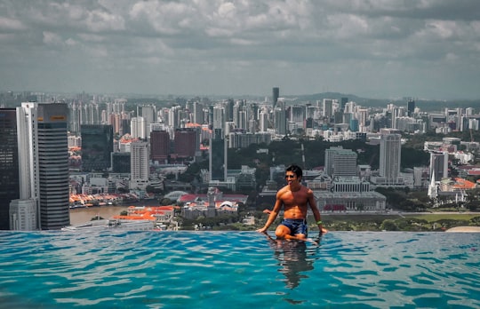 woman in black bikini top sitting on swimming pool during daytime in Marina Bay Sands Singapore