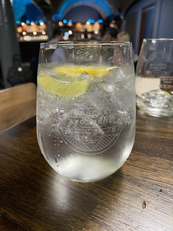 A chilled glass of fizzflow soft drink with ice cubes and a slice of lemon on the rim.