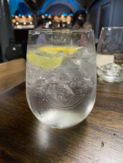 Close-up of fizzing soft drink pouring into a glass with ice cubes and a slice of lemon.