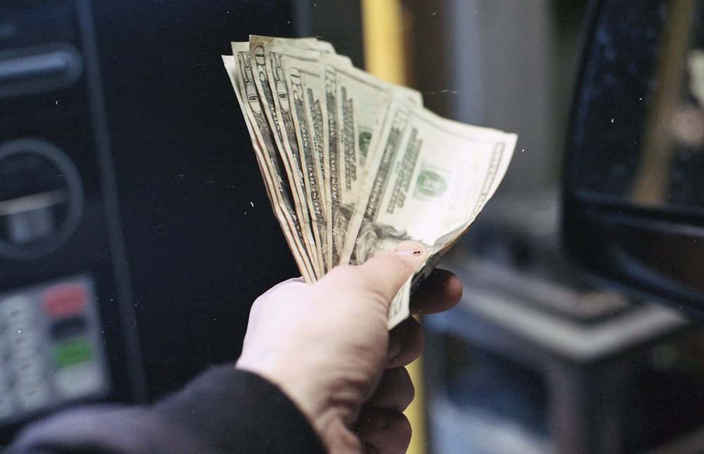 Persona que sostiene un abanico de billete de un dólar estadounidense