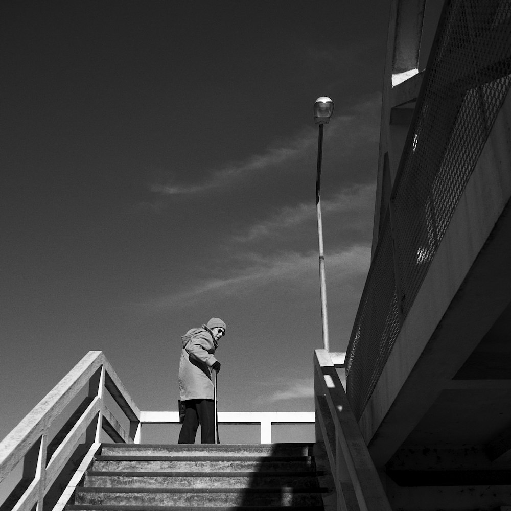 a black and white photo of a person standing at the top of a flight of