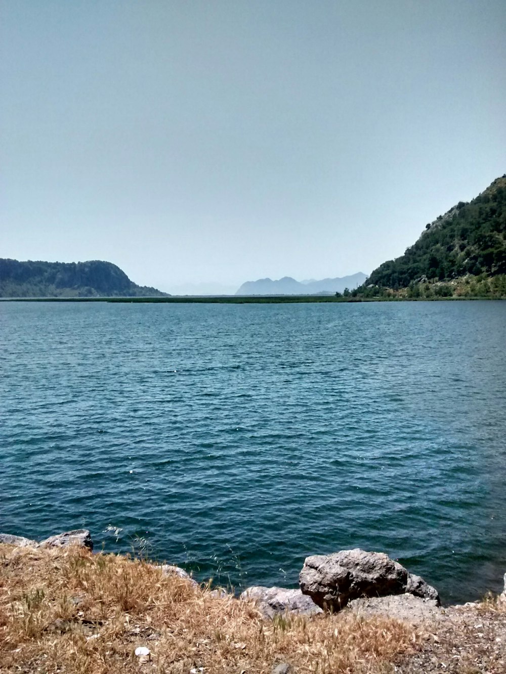 body of water near mountain during daytime