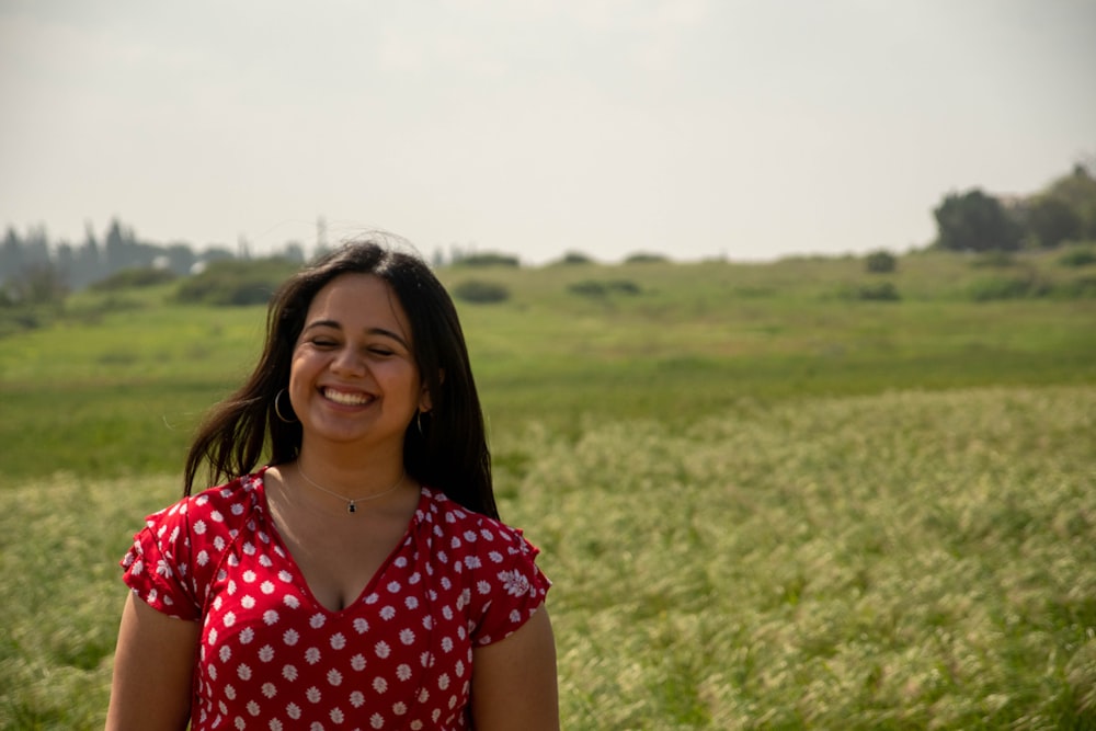 woman in red and white polka dot shirt standing on green grass field during daytime