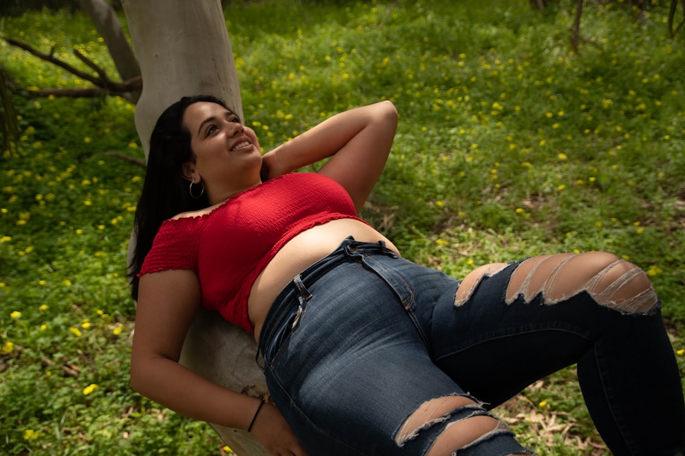 woman in red tank top and blue denim shorts lying on ground