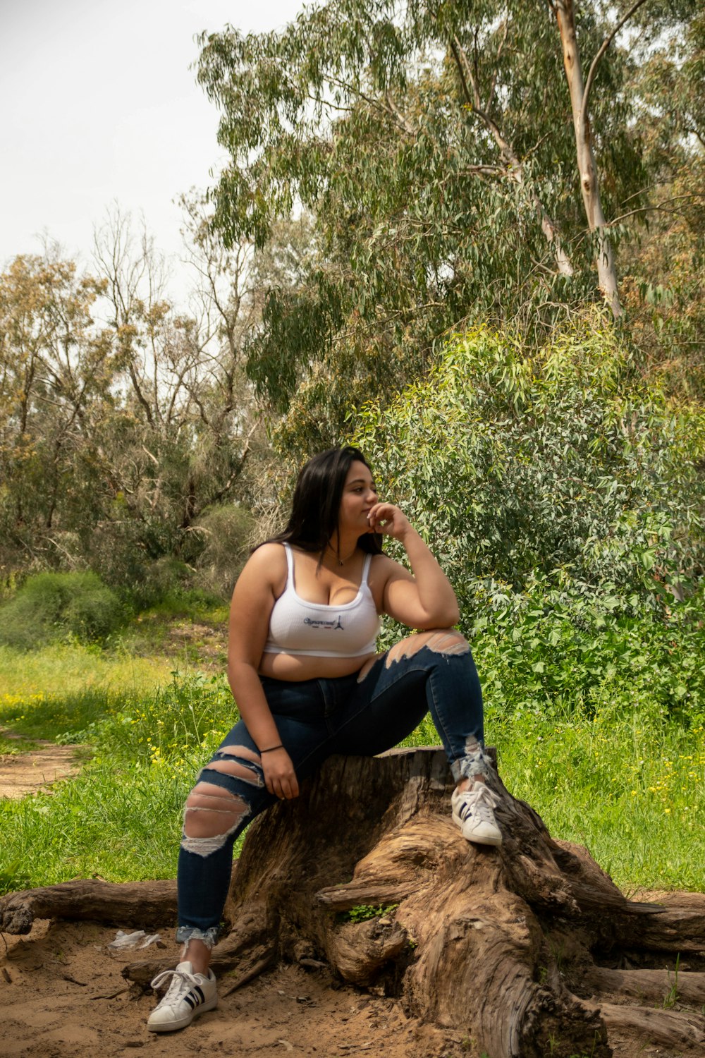 woman in blue t-shirt and blue shorts sitting on brown tree log during daytime