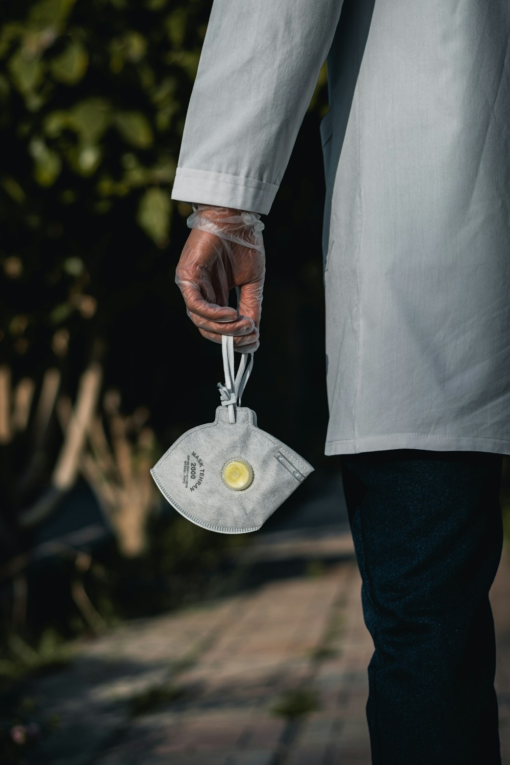 person in white dress shirt and blue denim jeans holding silver round pendant