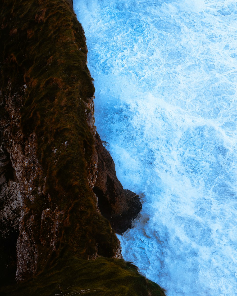 brown rocky mountain beside body of water during daytime