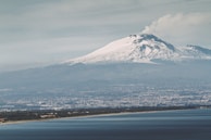 snow covered mountain near body of water during daytime