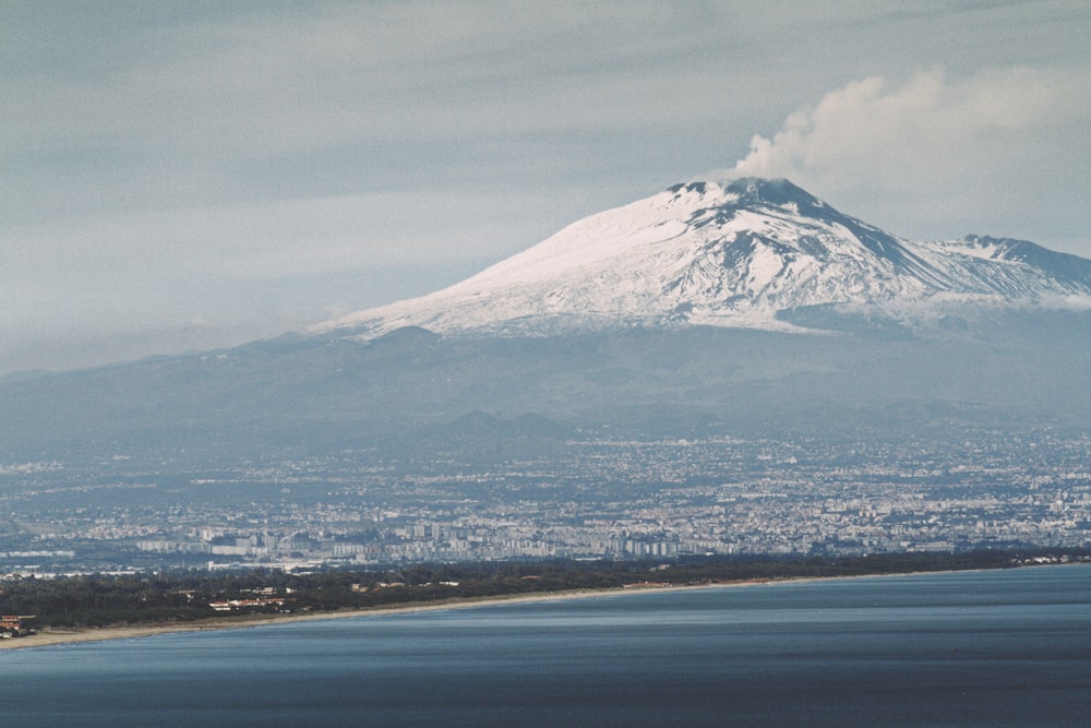 montagne enneigée près d’un plan d’eau pendant la journée