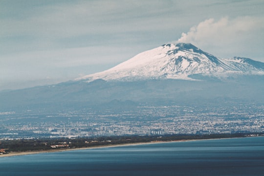 snow covered mountain near body of water during daytime in Catania Italy