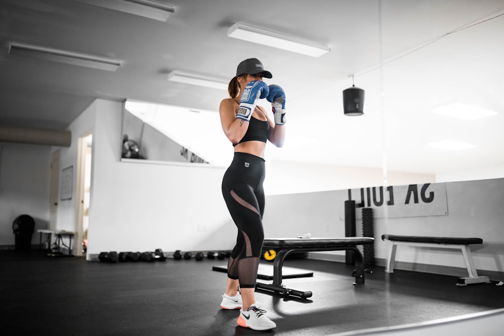 femme en chemise orange et noire et leggings noirs faisant de l’exercice