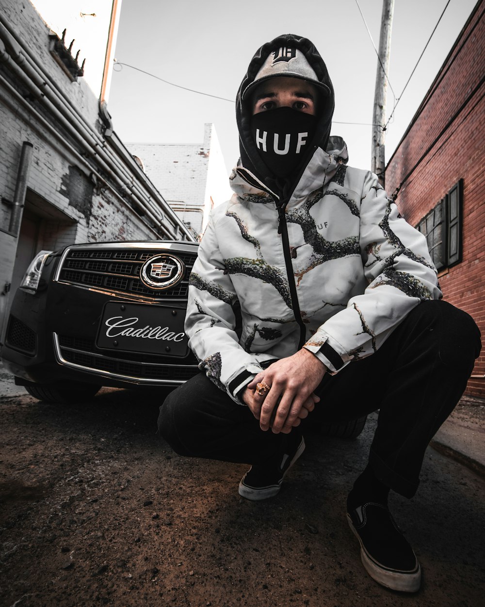 man in gray jacket and black pants sitting on black mercedes benz car