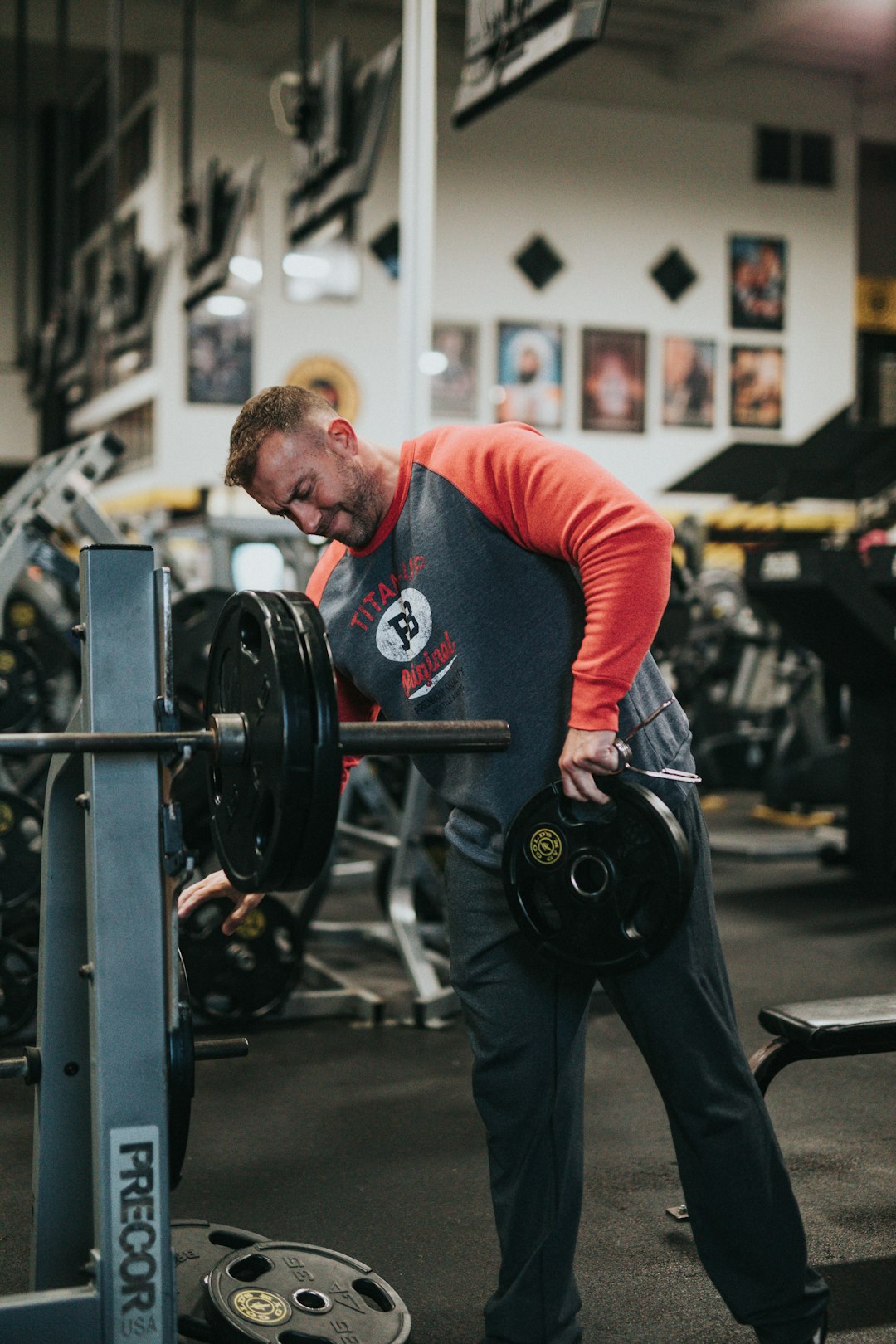 man in red long sleeve shirt carrying black barbell