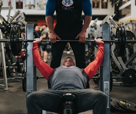 Personal trainer helping spot a bench press, coaching a client through the exercise