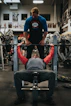 man in black crew neck t-shirt and gray pants sitting on black and red bench