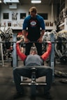man in black crew neck t-shirt and gray pants sitting on black and red bench