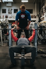 Personal trainer helping spot a bench press, coaching a client through the exercise