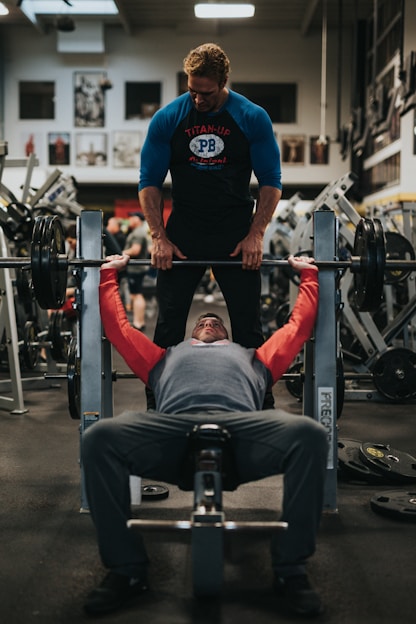 Personal trainer helping spot a bench press, coaching a client through the exercise