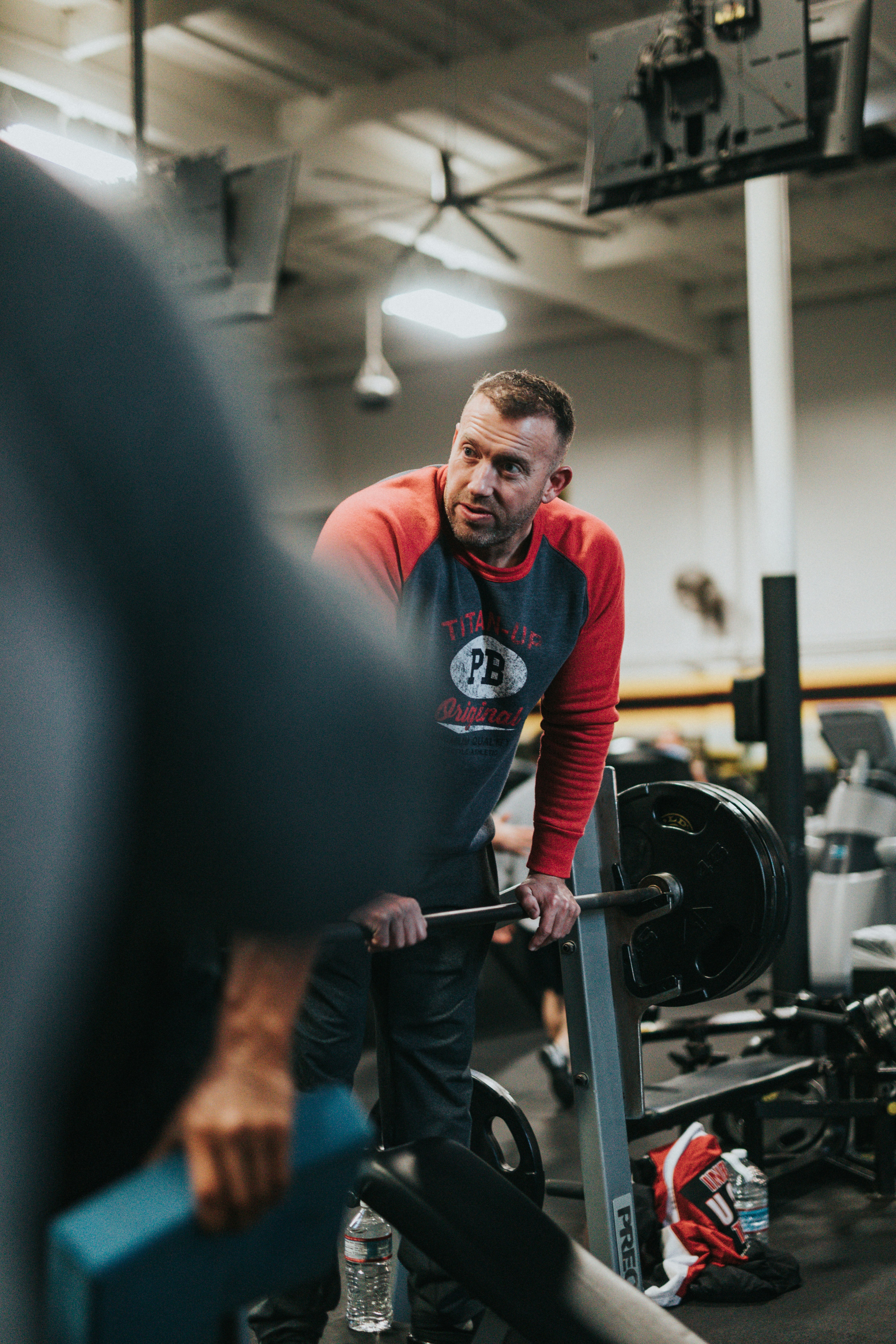 man in red and white crew neck long sleeve shirt holding black barbell