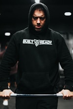 Close-up of a red and black Crossfit WCG hoodie stretched during an intense workout.