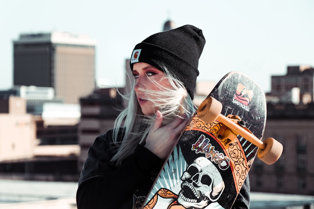 woman in black jacket drinking orange and black plastic bottle