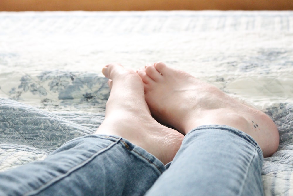 person in blue denim shorts lying on white sand during daytime