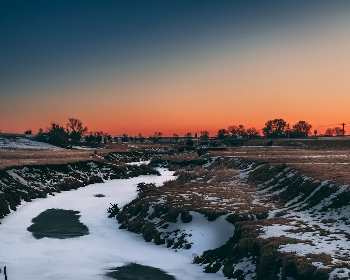 A creek winding through Iowa farmland at dusk