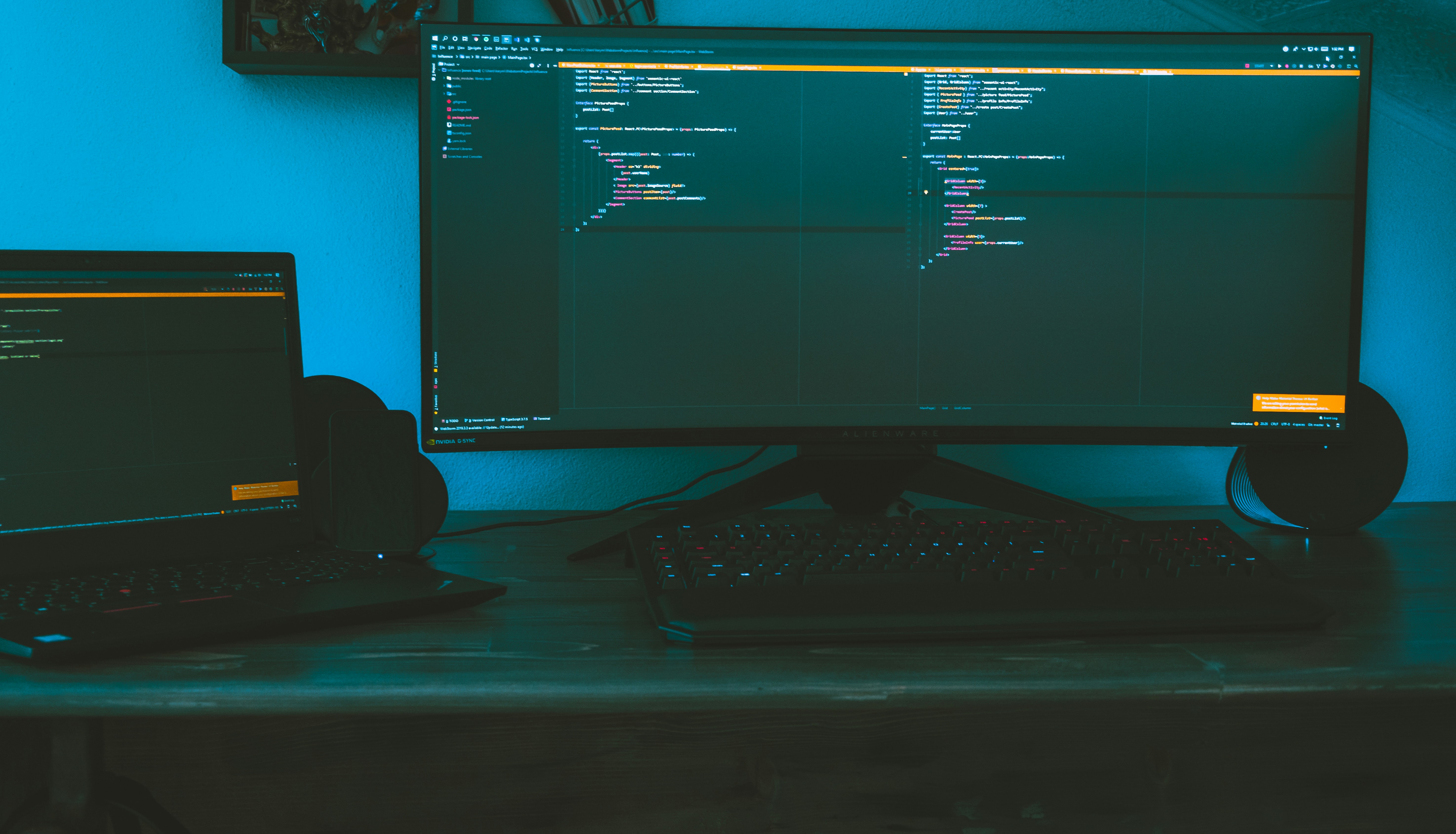 A sleek workspace featuring dual monitors displaying data dashboards and code, bathed in soft blue light.