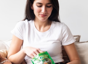 woman in white crew neck t-shirt holding green plastic pack