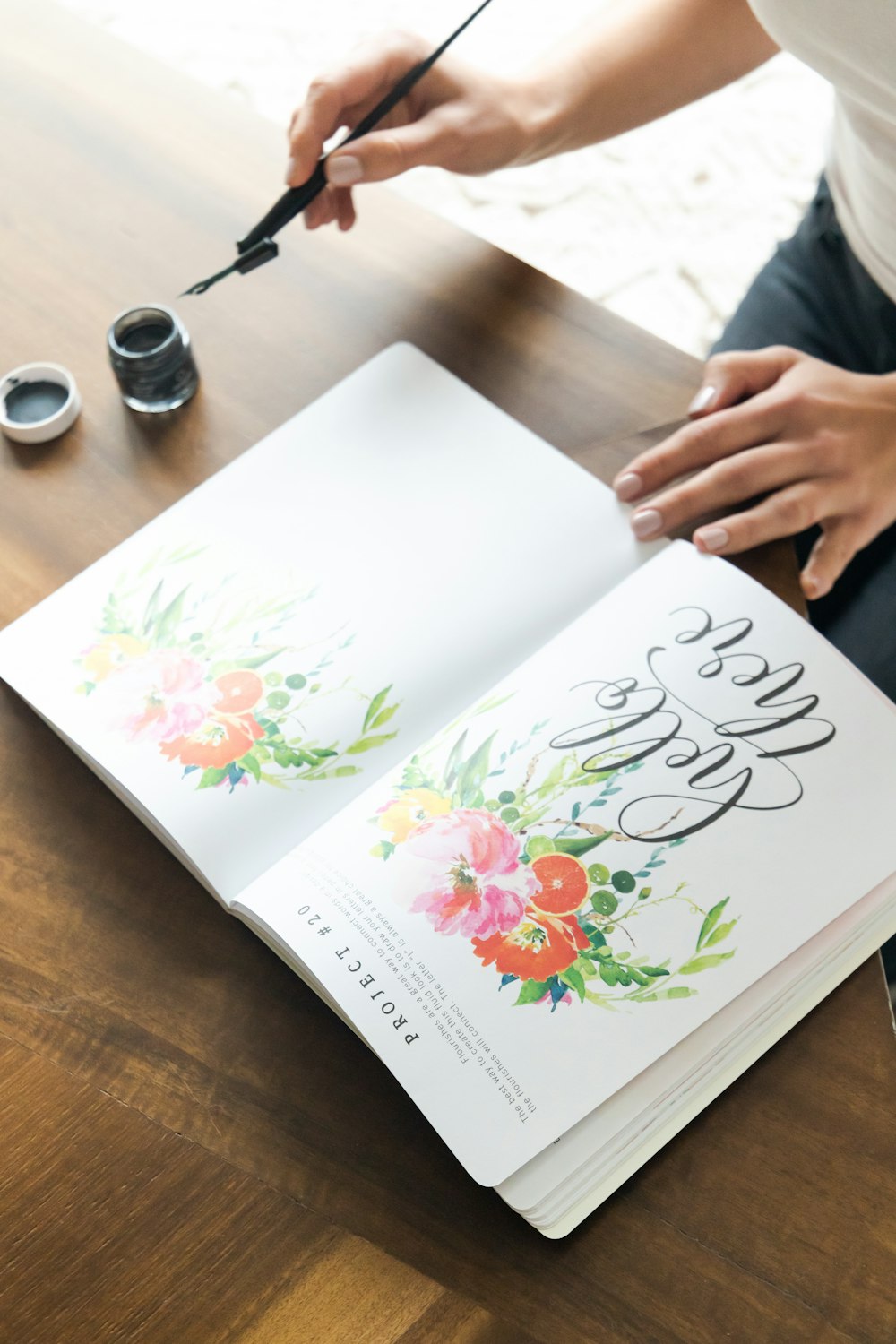 person holding white and pink floral book