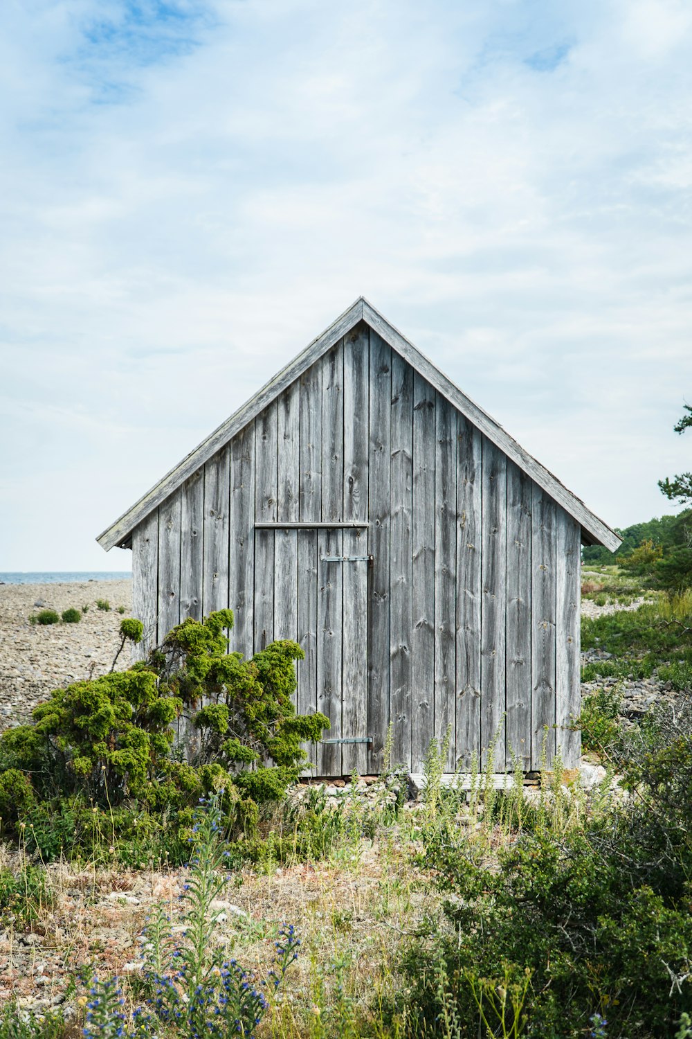 brown wooden house on green grass field under white clouds during daytime