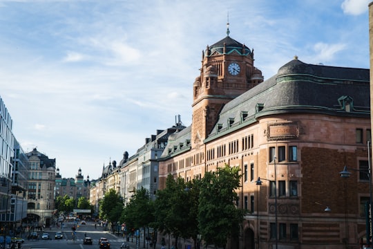 cars parked in front of brown concrete building during daytime in Vasagatan, Stockholm Sweden